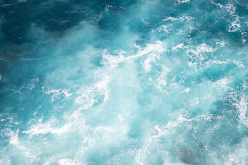 Fototapeta premium Looking at water movement of ocean creating white spray waves texture lit by sunlight simple minimal natural background