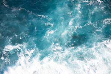 Looking at water movement of ocean creating white spray waves texture lit by sunlight simple...