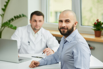 A bald male patient is rejoicing in the success of his healing near a caucasian doctor in a white...