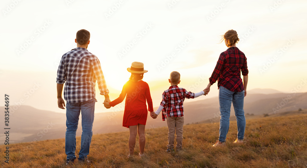 Poster happy family: mother, father, children son and daughter stand with their backs holding hands on suns