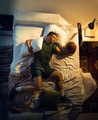 Passioned. Top view of young professional basketball player sleeping at his bedroom in sportwear with ball. Loving his sport even more than comfort, playing match even if resting. Action, motion