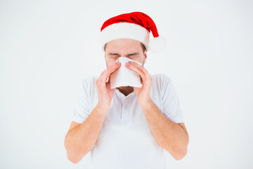 Fototapeta na wymiar Young man isolated over white background. Guy in red christmas hat celebrate festive new year. Sick ill person sneezing into white tissue.
