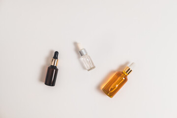 White, orange and black serum bottles on white background. Cosmetic mockup. Place to insert text, images. Top view. Flat lay.