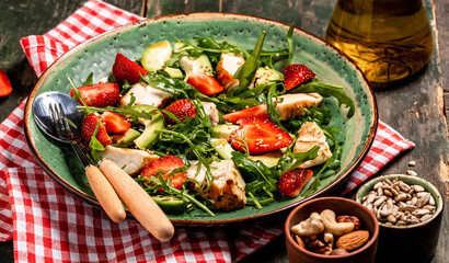 Fresh strawberry salad with arugula, chicken, avocado and strawberries. Plate with a keto diet food. Top view, Food recipe background. Close up