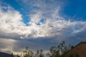 Dark, gray and white rain clouds over a windy rainy city in spare sunlight in autumn, Almere,...