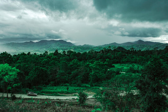 Top view of landscape dark green mountain road with raining cloudy sky, Beautiful dark green mountain view