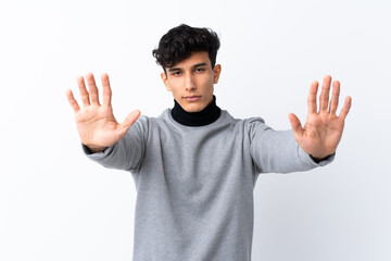 Young Argentinian man over isolated white background making stop gesture and disappointed