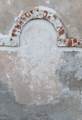 an old peeling wall with fallen plaster and a brick arch
