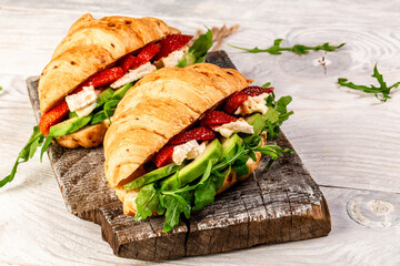 Breakfast, business lunch, sandwiches Croissant with strawberries and soft cheese with mold brie camembert on wooden background. banner menu recipe top view