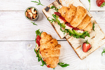 Breakfast, business lunch, sandwiches Croissant with strawberries and soft cheese with mold brie camembert on wooden background. banner menu recipe top view