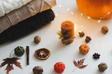 Fototapeta na wymiar Cozy autumn composition. Pumpkin, wax candles, leaves. Hygge lifestyle, cozy autumn mood. Halloween, Happy Thanksgiving concept