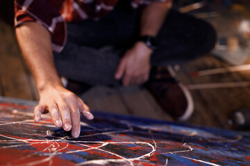 Artist works on abstract oil painting draws with his hands on the large canvas in creative modern studio. Abstract modern art.