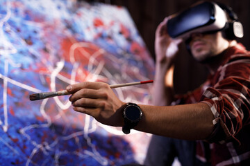 Talented male artist wearing virtual reality headset in creative modern studio. Artist works on...
