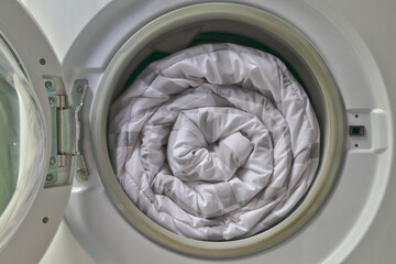 Duvet rolls inside washing machine , Cleaning white blanket. 