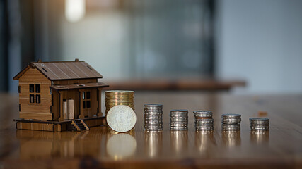 Mini house designs and piles of coins that are lined up like graph on wooden blocks. Planning ideas for real estate investments, home savings & buying, mortgages, loans, banking, tax accounting.