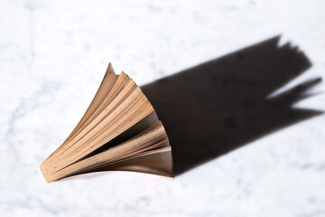 A woman holding a book flicking through the pages against a black blank background