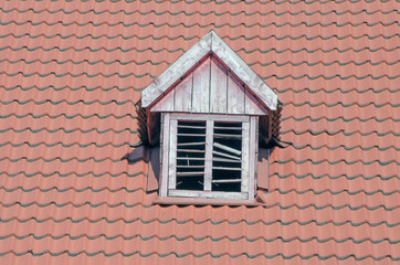 Brown tiled roof of a detached house. Ventilation window.