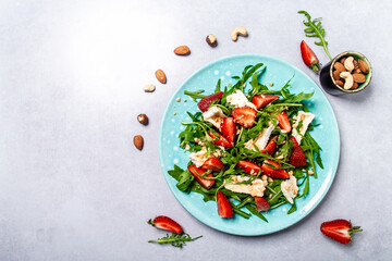 Summer Strawberry Salad with arugula, strawberries and cheese brie, camembert in a plate. Vegan food. Healthy food concept, Top view