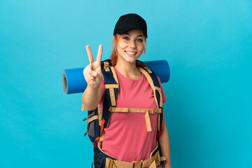 Teenager Russian hiker girl isolated on blue background smiling and showing victory sign
