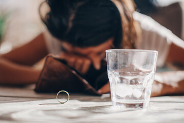 Financial difficulties concept, young frustrated woman sitting next to an old empty wallet.
