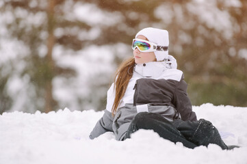 Fototapeta na wymiar active little healthy sport kid girl in ski suit and goggles sitting in snow at mountain winter resort with copy space during vacation holiday