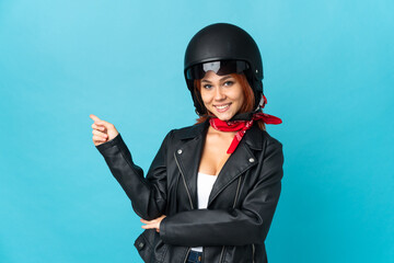 Teenager biker girl isolated on blue background pointing finger to the side