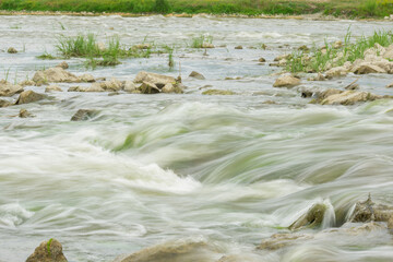 The flow of the river in the summer forest. Stones washed by water. Reflection on the water. water movement for a long exposure.
