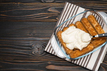 tiramisu dessert cooking - Traditional Italian Savoiardi ladyfingers Biscuits and cream in glass baking dish on wooden background