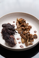 Baked lamb chops and mushrooms on a white plate.