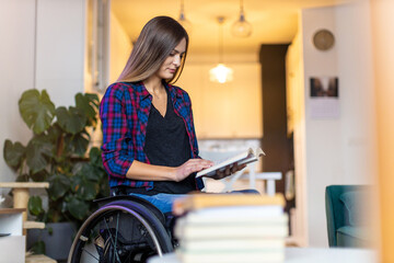 Woman in wheelchair reading book at home
