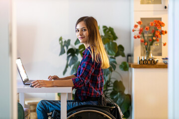 Young woman in wheelchair using laptop at home
