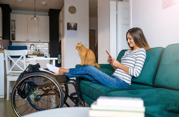 Disabled young woman using smartphone while sitting on sofa at home
