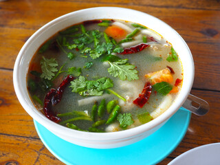 spicy asian retail catfish soup with vegetables (Tom Yum) on wooden table