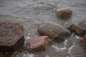 Rocks on the shore washed by dark water