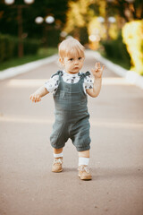 a happy child dressed in a muslin jumpsuit is resting on the green grass.