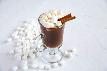 Coffee in glassware with marshmallows and cinnamon on a white table background