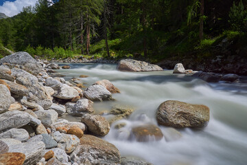 Langzeitbelichtung eines Wasserlaufs &uuml;ber Steine in den Bergen mit seidenem Wasser