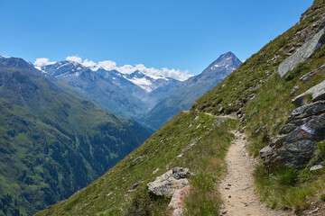 Bergweg am Rand eines gr&uuml;nen Berges beim Wandern in den Bergen Alpen Wanderweg