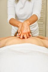 Young woman receiving a back massage in a medical center. Female patient is receiving treatment by professional therapist with beautiful hands. Body positive, harmony, healthy lifestyle