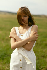 Nice picnic on the grass. Young beautiful woman in the middle of green field. Summer landscape, good weather. Windy day with sun and clouds. Cotton white suit eco style. 