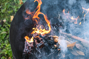 Burning in  barrel of autumn yellow maple leaves with flames and charcoals, the view from above, a lot of smoke, goodbay autumn summer, autumn mood