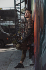 Fototapeta na wymiar Mexican Latin young man leaning on the wall, urban portrait wearing military clothing
