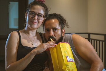 Pareja de novios casados comiendo palomitas viendo television pelicula en casa terror miedo