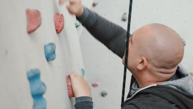 Rock climber climbing the wall with hooks, working hard, overcoming himself