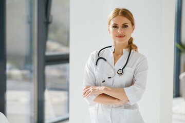 Portrait of young woman doctor with white coat standing in hospital