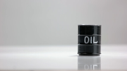 Single oil barrel on white background. Black barrel on reflective surface.
