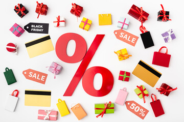 Top view of percent sign with credit cards and toy shopping bags on white background