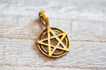Brass golden color pentagram necklace on wooden background