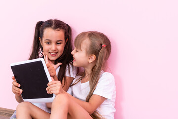 Little girls playing on a tablet computing device on the floor