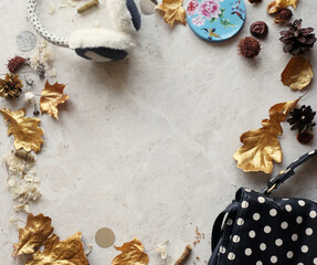 Fototapeta na wymiar frame with fashionable bag, warm headphones, dry golden leaves, chestnuts, cones and petals. Autumn or fall scene. Top view, flat lay, copy space.